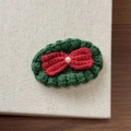 Detailed macro shot of handmade knitted Christmas tree hair clip with white pearl and gold trim - Red Bow