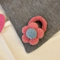 Élastique à cheveux fleur en peluche rose et bleu posé sur un tissu gris texturé - Fleur Rose Rouge
