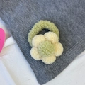 Vista de detalle del coletero de flor de peluche hecho de tejido suave verde y beige - Flor Amarilla
