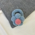 Detalle del coletero de flores de felpa con pétalos azules y pompón rosa en el centro - Flor Azul