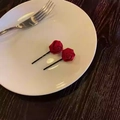 Close-up of two red silk rose hair clips with black metal pins on a decorative plate - Rose Style