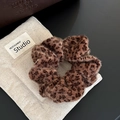Detalle de un coletero de felpa con estampado de leopardo y textura suave sobre fondo beige - Coletero