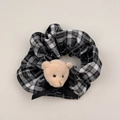 Dettaglio dell'elastico a scacchi con orsetto di peluche e fiocco in nastro nero - Quadri Nero e Grigio