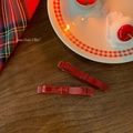 Macro shot of two glossy dark red resin bow hair clips on a vintage wooden surface - Red
