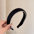 Dettaglio del cerchietto in peluche nero con cuciture a onda argentate e texture morbida - Nero