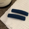 Dettaglio dei fermagli per capelli in feltro blu scuro su carta con finitura morbida - Blu
