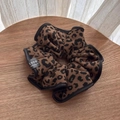 Vista dettagliata di elastico scrunchie leopardato con trama morbida ed etichetta - Leopardo Caffè