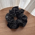 Dettaglio di scrunchie leopardato grigio con morbida texture spazzolata ed etichetta nera - Leopardato Nero