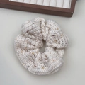 Nahaufnahme von cremefarbenem Strick-Haargummi mit bunten Sprenkeln und Webstruktur - Beige Scrunchie