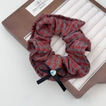 Dettaglio di scrunchie a quadri rossi con fiocco nero e strass scintillante a cuore - Elastico per capelli a quadretti rossi