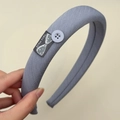 Detailaufnahme des staubblauen, gepolsterten Stoffstirnbands mit Handmade-Label und Knopf - Einfarbig Roter Samt