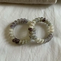 Close-up of marble-patterned spiral hair ties in gray-purple and cream on fabric - Gradient Grey Yellow