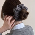 Detail van een grijze fluwelen scrunchie die een knotje stylet met fijne naad - Grijs