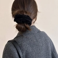 Detail van een zwarte fluwelen haarelastiek gestyled in een klassieke knot-look - Zwart