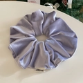 Detail showing soft lavender velvet scrunchie texture with premium branded woven label - Purple