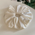 Close-up of cream velvet scrunchie with soft texture and elegant small black woven label - Milk White