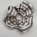 Großaufnahme eines gestreiften Seiden-Scrunchies in Beige und Schwarz auf weißem Grund - Weiße Gestreifter Rüschen-Scrunchie