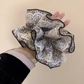 Nahaufnahme eines floralen Haargummis mit weißer Spitze und schwarz-weißem Muster - Beige Serie