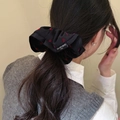 Detail view of a large black satin scrunchie with red hearts worn on a low ponytail - Black