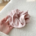 Close-up of soft pink scrunchie with diagonal twill texture and natural folds for hair styling - Pink