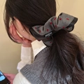 Detail of grey knitted hair scrunchie with red heart embroidery and black branded label - Gray