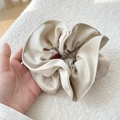 Close-up of a large beige pleated scrunchie with soft fabric texture in a hand-held shot - Beige