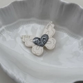 Primer plano de pinza de mariposa con grabado LOVE en corazón y brillantes diamantes - Blanco Roto
