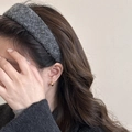 Primer plano de una diadema de lana gris oscuro usada por una modelo con pendientes dorados - gris oscuro
