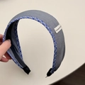 Close-up of grey fabric headband with blue checkered edges and handmade woven label - Headband