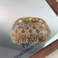 Detail of amber marble acetate hair claw with hollow waffle pattern and gold logo - Light Coffee