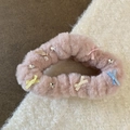 Détail d'un chouchou en peluche rose avec des nœuds en satin et des breloques étoiles - Chouchou / Nuage Rose
