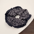 Dettaglio di un elastico per capelli nero a fiori con volant e stampe bianche - Elastico per capelli nero