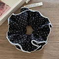 Polka-Dot-Haargummi mit weißen Wellenkanten auf Holzoberfläche mit Lifestyle-Requisiten - Schwarz