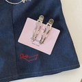 Detail of two wavy silver-tone hair clips on a pink card against denim fabric background - Hollow Wave