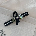 Detalle de una pinza para el pelo de cuero negro con pedrería y colgante de corazón LOVE - Negro