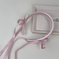 Nahaufnahme von rosa Satin-Haarreif mit langer Schleife auf beigem Tablett - Rosa