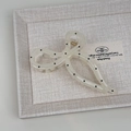 Detailopname van de haarklem met polkadots in crème acryl op een getextureerd blad - Crèmewit Stippen Strik Stijl