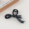 Detaillierte Nahaufnahme einer schwarz-weißen Haarklammer mit Punkten und Schleifen-Design - Schwarzer Knoten-Stil