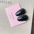 Close-up of black hair clips with white polka dots on pink display card on beige linen background - Black Oval Style