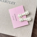 Close-up of two cream bow hair clips with black polka dots on a pink display card - Creamy White Bow Style A