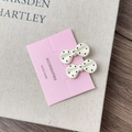 Detailed view of handmade bow hair clips with black polka dots on display card - Creamy White Bow Style B