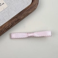 Dettaglio ravvicinato del fermaglio per capelli con fiocco di raso rosa e bordi tessuti - Rosa