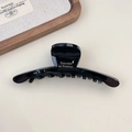 Detailed macro view of large glossy black acetate hair claw with golden French lettering - Style B Black