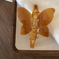 Detailed close-up of amber acetate butterfly hair claw with marble texture on wood tray - Coffee