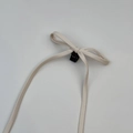 Detailopname van de crèmekleurige haarclip met kunstlederen strik en lange linten - Off-wit