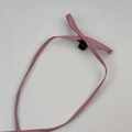 Detail van roze lederen strik haarspeld met stevige zwarte plastic mini-klauwbevestiging - Roze