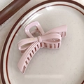 Detailopname van een roze strik haarklem met Franse letters op een keramisch bord - Roze