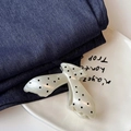 Dettaglio della molletta per capelli a fiocco crema con pois neri su jeans blu - Stile a V Bianco Crema