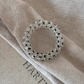Macro shot of transparent spiral hair tie with black polka dots on a linen texture - Transparent Black Dot