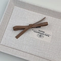 Detail view of a vintage dark brown leather bow hair clip with a metallic duckbill clasp - Brown